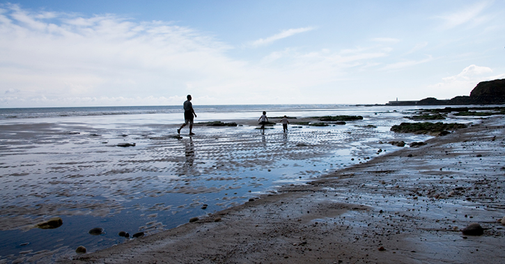 Father walking with two children on Seaham Beach, County Durham